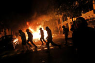 People run across a street during clashes between protestors and police in Barcelona, Spain, Wednesday, Oct. 16, 2019. Spain's government said Wednesday it would do whatever it takes to stamp out violence in Catalonia, where clashes between regional independence supporters and police have injured more than 200 people in two days. (AP Photo/Emilio Morenatti)