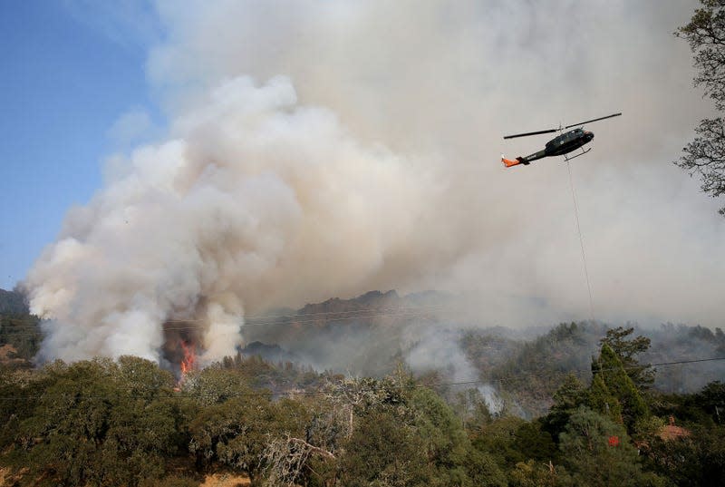 A helicopter refills water for an air drop as the Glass Fire burns about a mile out of downtown Calistoga, California, September 30, 2020. 