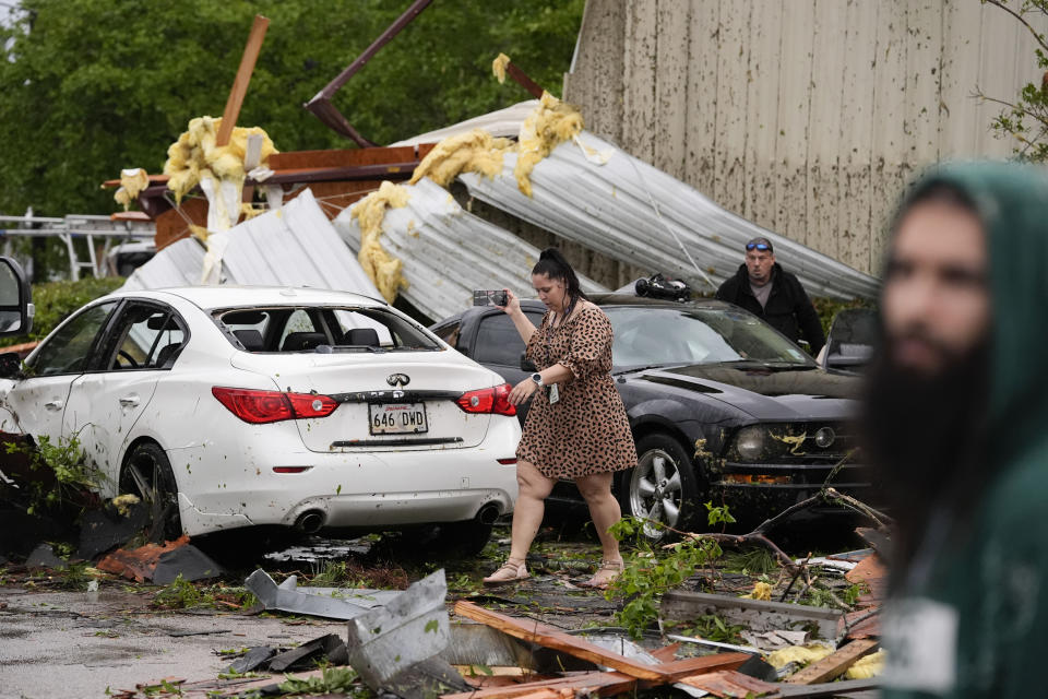 Robin Marquez, project coordinator for E.C.O. Builders, walks past her son's heavily damaged car after they sheltered in place inside the business, for what she said was a tornado, in the aftermath of severe storms that swept through the region in Slidell, La., Wednesday, April 10, 2024. (AP Photo/Gerald Herbert)