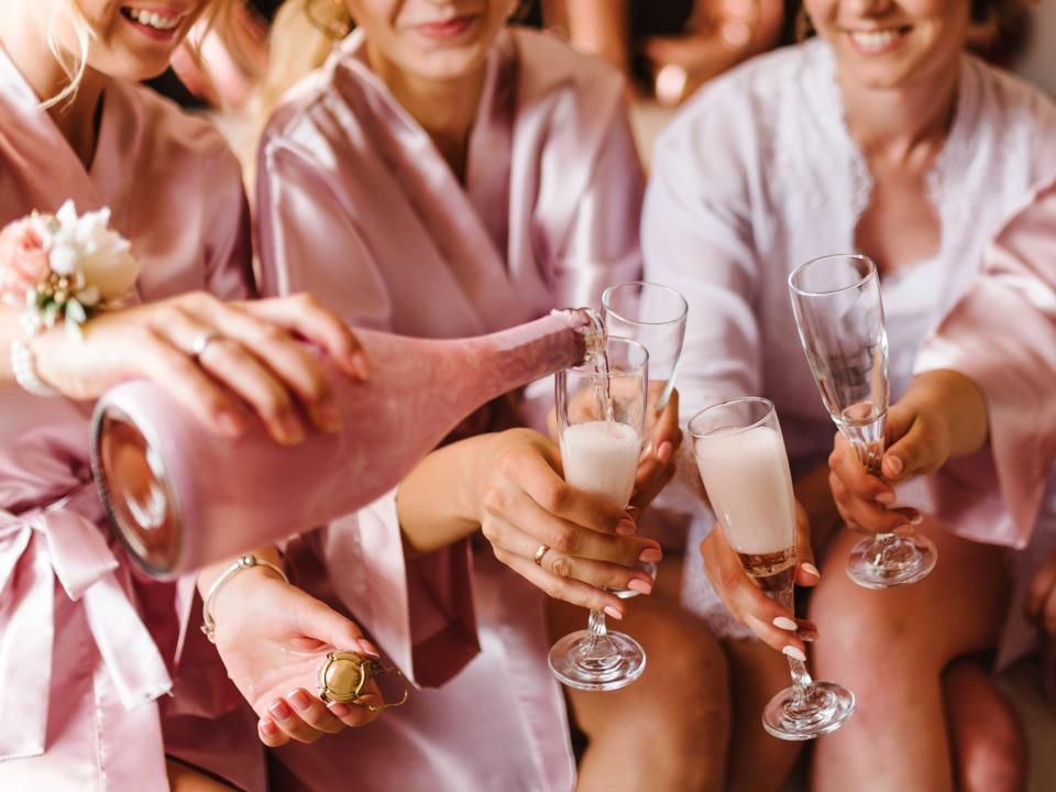 Bridesmaids in pink bathrobes pouring pink Champagne