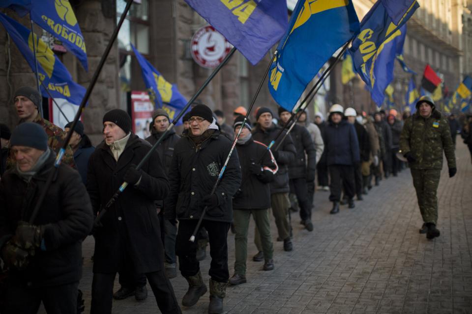 Supporters of a far-right Ukrainian party Svoboda march a long the street near to Kiev's Independence Square, the epicenter of the country's current unrest, Ukraine, Wednesday, Feb. 5, 2014. The mayor of a western city warned that his police would fight any troops sent in by the president. The governor of an eastern region posted an image of an opposition lawmaker beaten bloody, saying he couldn't contain his laughter. Two months into Ukraine's anti-government protests, the two sides are only moving further apart. (AP Photo/Emilio Morenatti)