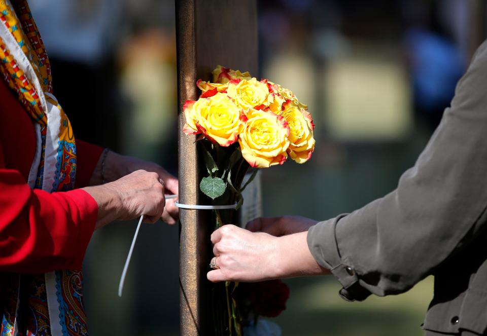 People tie roses to a chair following the 2023 Remembrance Ceremony at the Oklahoma City National Memorial & Museum in Oklahoma City, Wednesday, April, 19, 2023. 