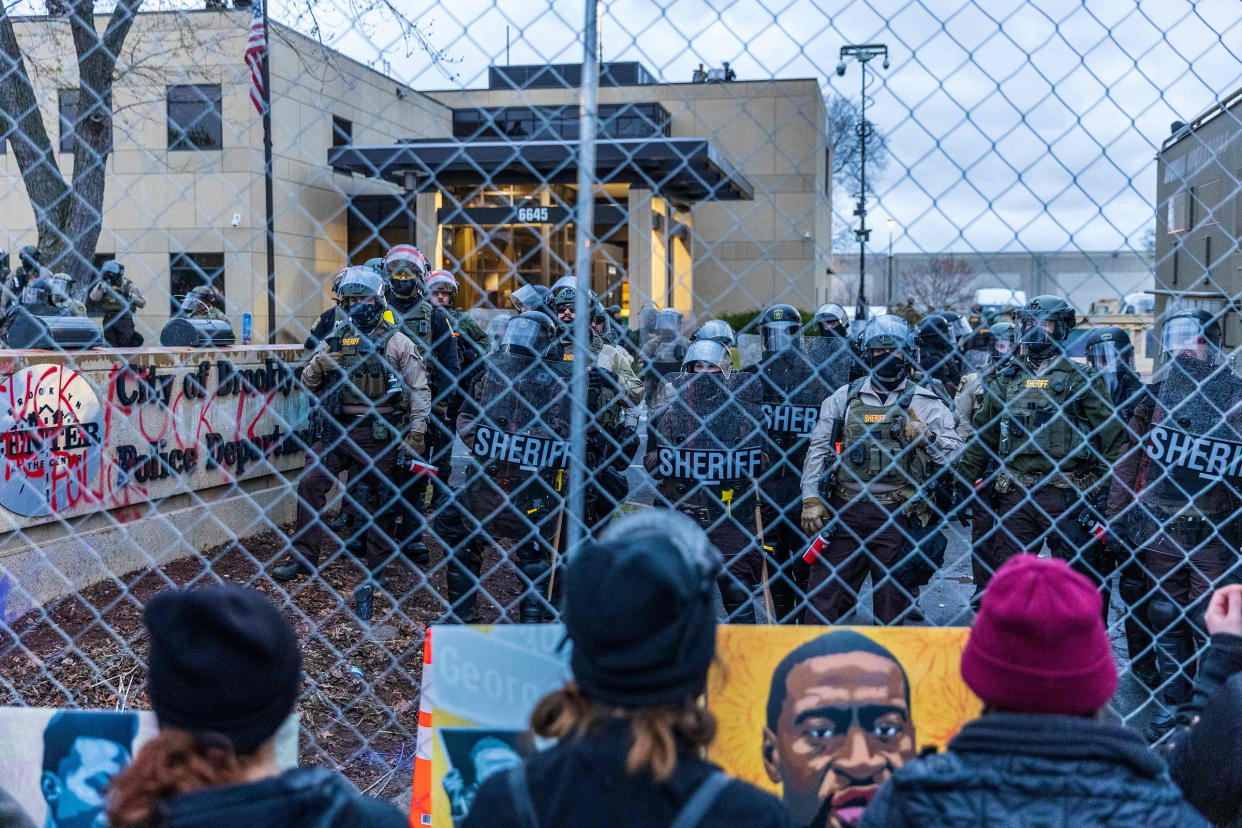 Sheriff officers stand guard outside the Brooklyn Center police station as demonstrators stand on the other side of the chain-link fence protesting the death of Daunte Wright who was shot and killed by a police officer in Brooklyn Center, Minn. on April 14, 2021.