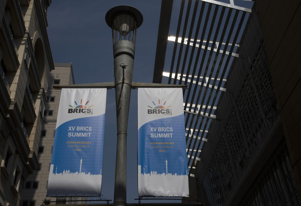 Carteles colgados en una farola en el exterior del Centro de Convenciones Sandton anuncian la celebración de la cumbre del bloque de los BRICS, en Johannesburgo, Sudáfrica, el 19 de agosto de 2023. (AP Foto/Denis Farrell)