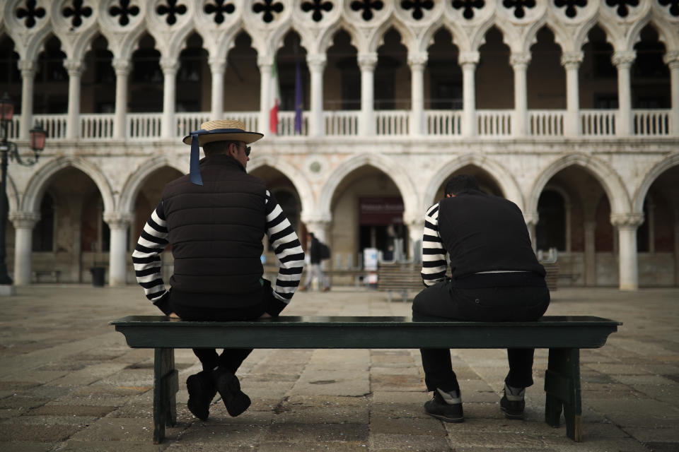 Gondoliers chat as they wait for customers near St. Mark's square in Venice, Italy, Tuesday, March 3, 2020. Venice in the time of coronavirus is a shell of itself, with empty piazzas, shuttered basilicas and gondoliers idling their days away. The cholera epidemic that raged quietly through Venice in Thomas Mann's fictional "Death in Venice" has been replaced by a real life fear of COVID-19. (AP Photo/Francisco Seco)