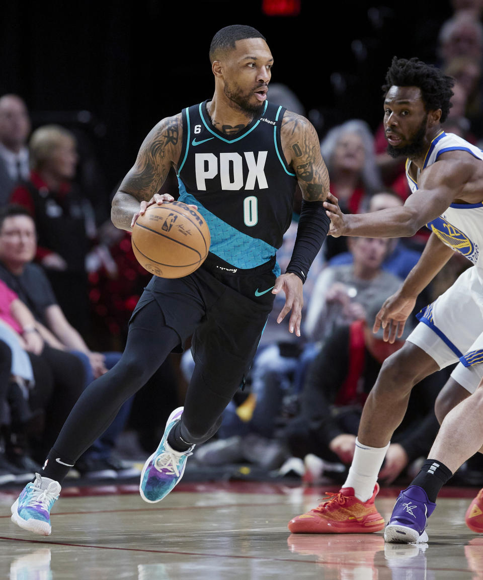 Portland Trail Blazers guard Damian Lillard, left, dribbles around Golden State Warriors forward Andrew Wiggins during the first half of an NBA basketball game in Portland, Ore., Wednesday, Feb. 8, 2023. (AP Photo/Craig Mitchelldyer)