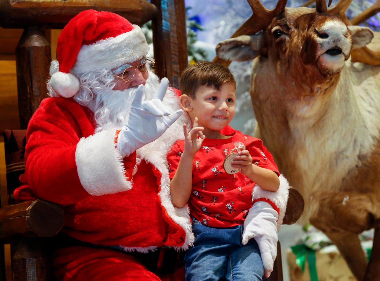 Skyler Perez, 5, and Santa Claus say "love" in sign language as they have their picture taken at Bass Pro Shops on Friday, Dec. 6, 2019. Santa was using sign language to communicate with deaf and hard-of-hearing children.