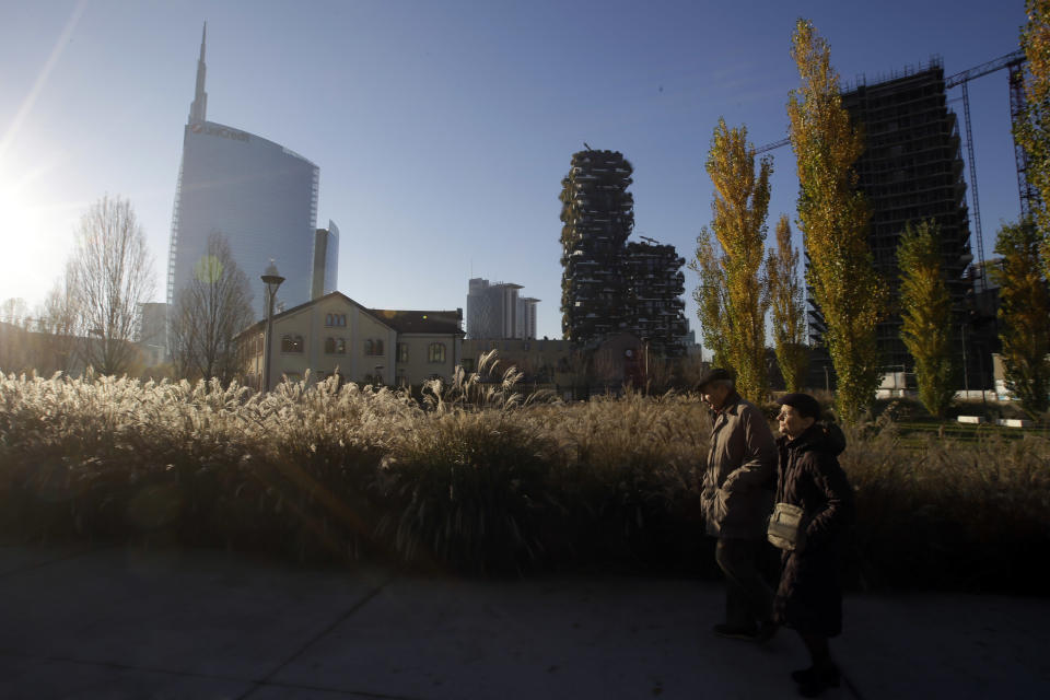 In this picture taken on Tuesday, Dec. 4, 2018 a man and a woman walk though the Tree Library park in Milan, Italy. If Italy's fashion capital has a predominant color, it is gray not only because of the blocks of uninterrupted neoclassical stone buildings for which the city is celebrated, but also due to the often-gray sky that traps in pollution. The city has ambitious plans to plant 3 million new trees by 2030_ a move that experts say could offer relief to the city’s muggy and sometimes tropical weather. (AP Photo/Luca Bruno)