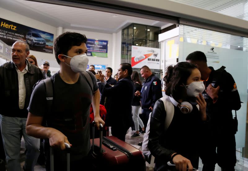Mexican students wear protective masks upon their arrival at the Del Bajio International Airport in Silao following their return from China