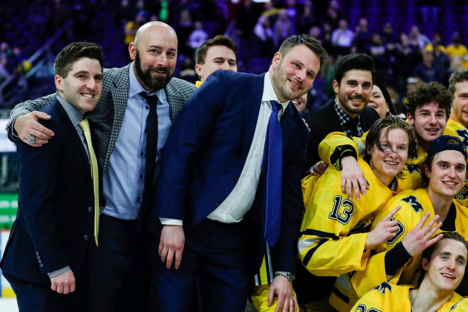 Michigan interim head coach Brandon Naurato, center right, associate head coach Bill Muckalt, center left, assistant coach Rob Rassey, center right, and director of hockey operations Topher Scott, left, pose for a photo with the Iron D trophy after a 4-3 overtime win against Michigan State of the "Duel in the D" at Little Caesars Arena in Detroit on Saturday, Feb. 11, 2023.