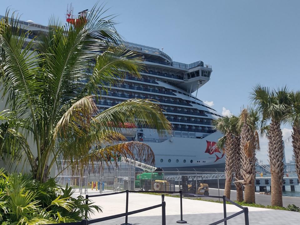 A cruise ship docked in port with palm trees.