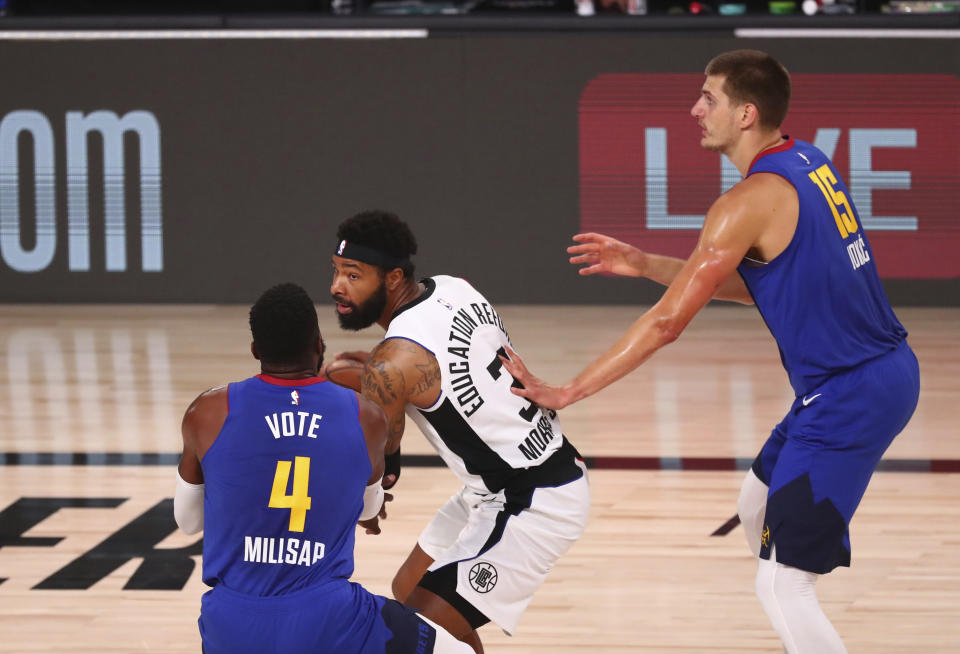 Los Angeles Clippers forward Marcus Morris Sr. (31) is defended by Denver Nuggets forward Paul Millsap (4) and center Nikola Jokic (15) in the first half of an NBA basketball game Wednesday, Aug. 12, 2020, in Lake Buena Vista, Fla. (Kim Klement/Pool Photo via AP)