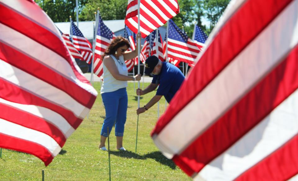 Kim Willis of the Michigan Department of Health and Human Services placed an American flag at the Early Bird Exchange Healing Hill of Hope at ceremony on Thursday.