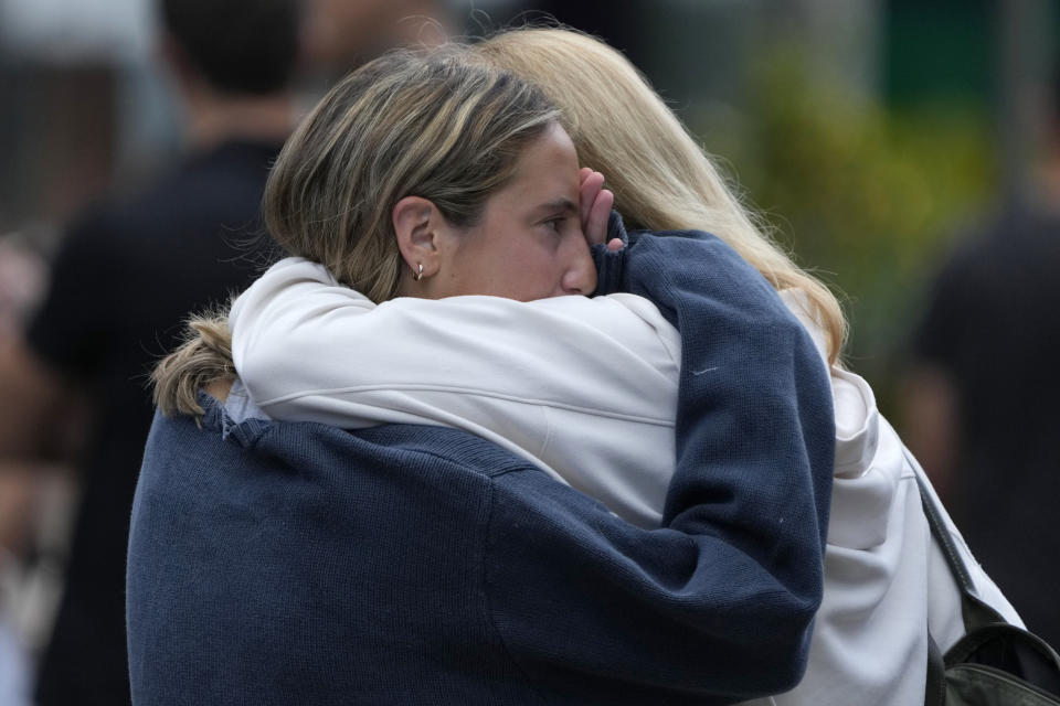 Two women embrace after leaving flowers as a tribute near a crime scene at Bondi Junction in Sydney, Sunday, April 14, 2024, after several people were stabbed to death at a shopping center Saturday. Police have identified Joel Cauchi, 40, as the assailant that stabbed several people to death at a busy Sydney shopping center Saturday before he was fatally shot by a police officer. (AP Photo/Rick Rycroft)