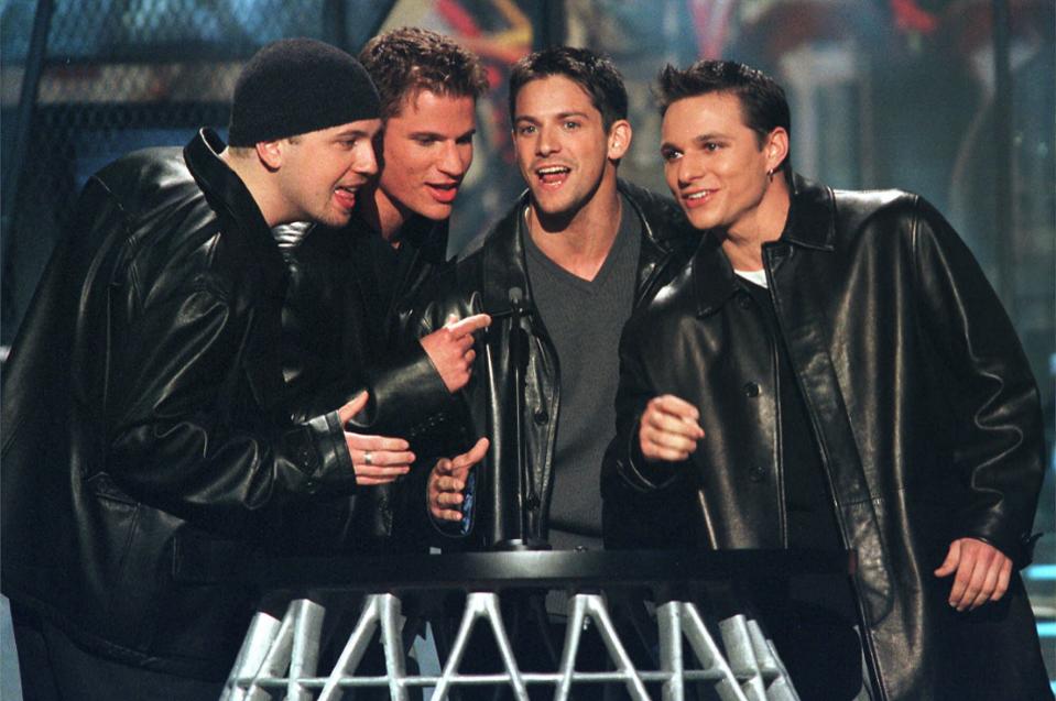 FILE - In this Oct. 28, 1999 file photo, the group 98 Degrees sings an introduction to singer Faith Hill at the WB Radio Music Awards at the Mandalay Bay Resort in Las Vegas. 98 Degrees was one of the most popular boy bands in the world, selling millions of albums and dominating the music scene in the 90s and 2000s with other groups like *NSYNC and the Backstreet Boys. (AP Photo/Laura Rauch, file)