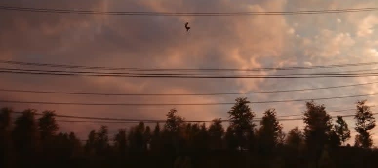 Spider-Man swinging over some trees next to some power lines in "Spider-Man: No Way Home"