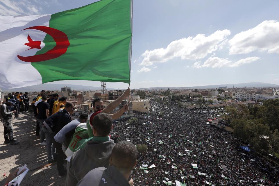 A demonstrator holds an Algerian flag during a protest in Bordj Bou Arreridj, east of Algiers, Friday, April 26, 2019. Algerians are massing for a 10th week of protests against their country's ruling class, calling for the ex-president's brother to be put on trial. (AP Photo/Toufik Doudou)
