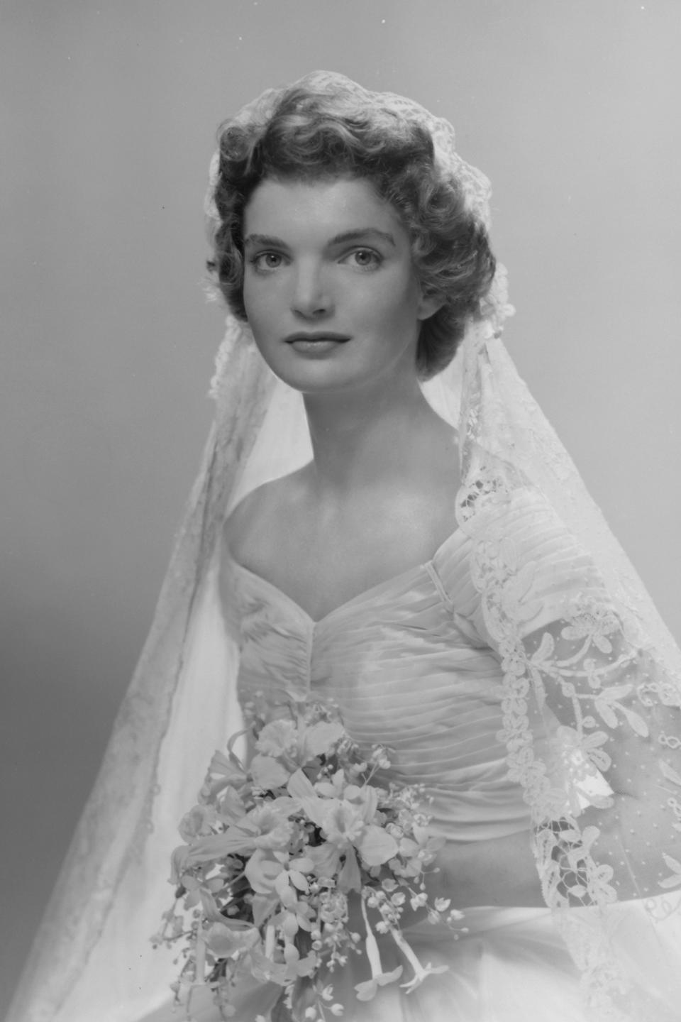 Bridal portrait of Jacqueline Lee Bouvier (1929 - 1994) shows her in an Anne Lowe-designed wedding dress, a bouquet of flowers in her hands, New York, New York, 1953. (Photo by Bachrach/Getty Images)
