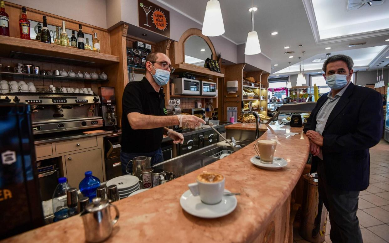 Customer stands at coffee bar in reopened Italian business - AFP