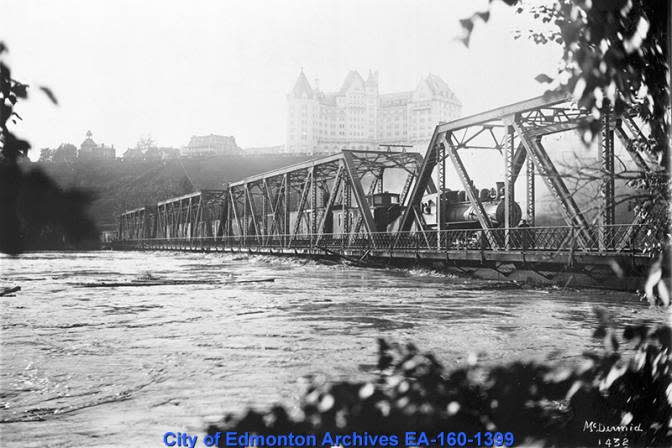 Fast-moving water threatened to destroy the Low Level Bridge in 1915. Train cars loaded down with sand were backed onto the bridge deck to prevent it from washing away. 
