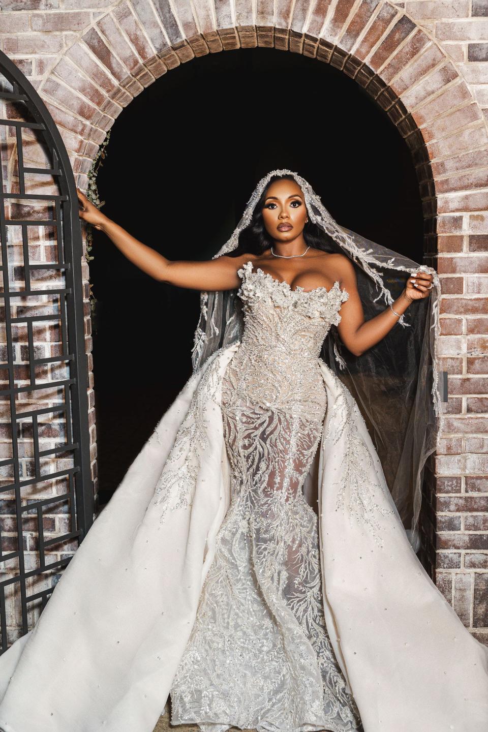 A bride stands in her wedding dress under an archway.