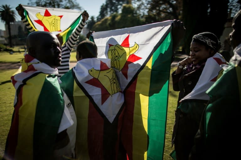 Zimbabwean "myflag" activists draped in their national flag sgather in Pretoria on July 14, 2016 prior to a march to the Zimbabwean embassy