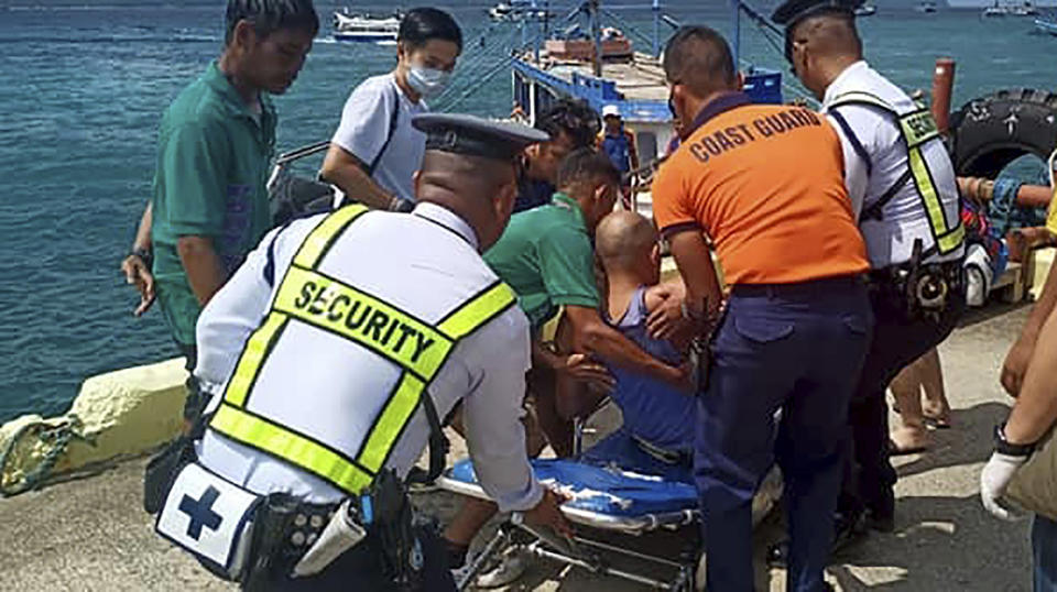In this photo provided by Philippine Coast Guard in Manila, coast guard personnel carry a survivor to a waiting ambulance after being rescued from a capsized dragon paddle boat off Boracay island resort Wednesday, Sept. 25, 2019, in the central Philippines. The coast guard says seven rowers drowned and 14 others were rescued when their dragon boat was suddenly lashed by strong waves and overturned in the central Philippines. (Philippine Coast Guard Via AP)