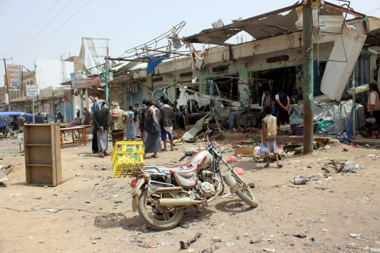 Yemenis gather next to a destroyed bus at the site of a Saudi-led coalition air strike in Saada province on August 10, 2018