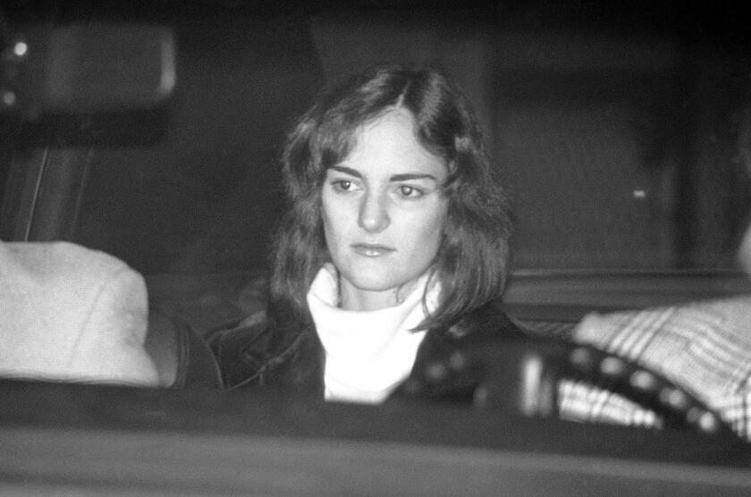 An unsmiling Patty Hearst is seated in a U.S. Marshal's car, leaving the Sam Mateo County jail in Redwood City, Calif., Thursday, Dec. 12, 1975, on her way to San Francisco to an appearance in federal court. The odd cast in her eyes is caused by the flash bouncing back. (AP Photo/Sal Veder)