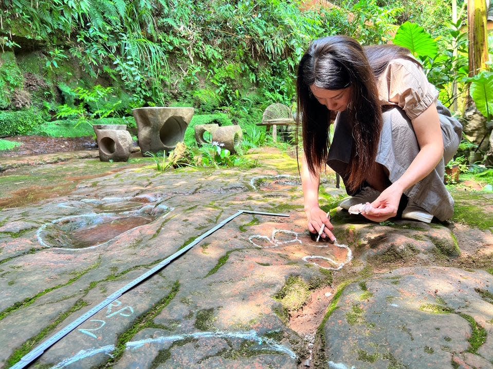 A paleontologist team member from Dr. Lida Xing's team measures the discovery of a dinosaur footprint in the courtyard of a restaurant in China.
