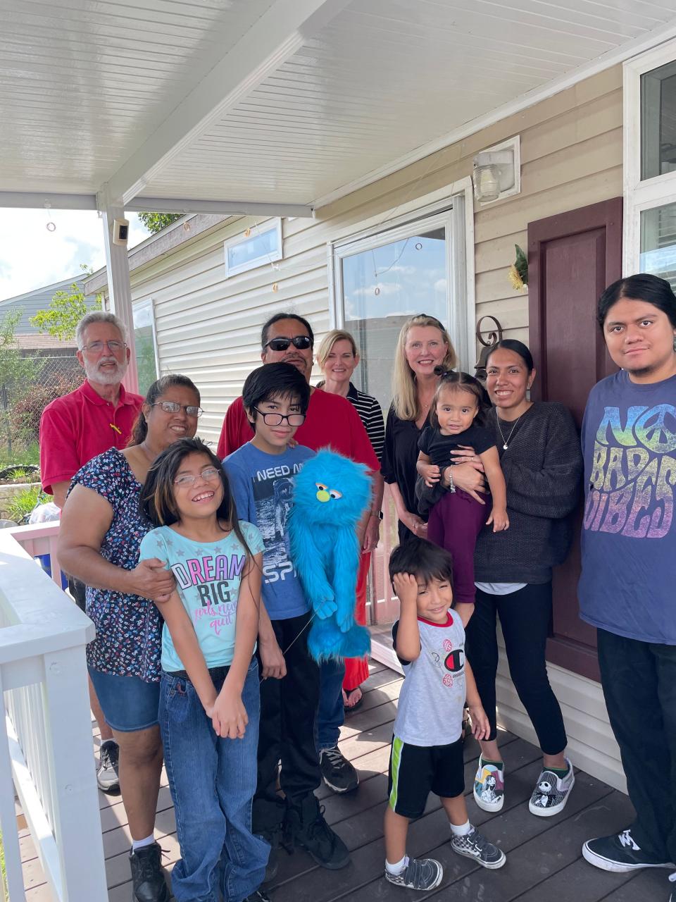 Danny Scott of CG&S Design-Build, back left, along with Beth Unite and Julie Phillips, back right, of Wonders & Worries met with the Trujillo family on their new covered porch and wheelchair ramp. Three generations of the family — Betty, Eliza, Ruben, Margarito, Domingo, Kayla, Marylinda, and Ruben Jr. — can now enjoy sitting out on the porch as well as getting into and out of the house easily.