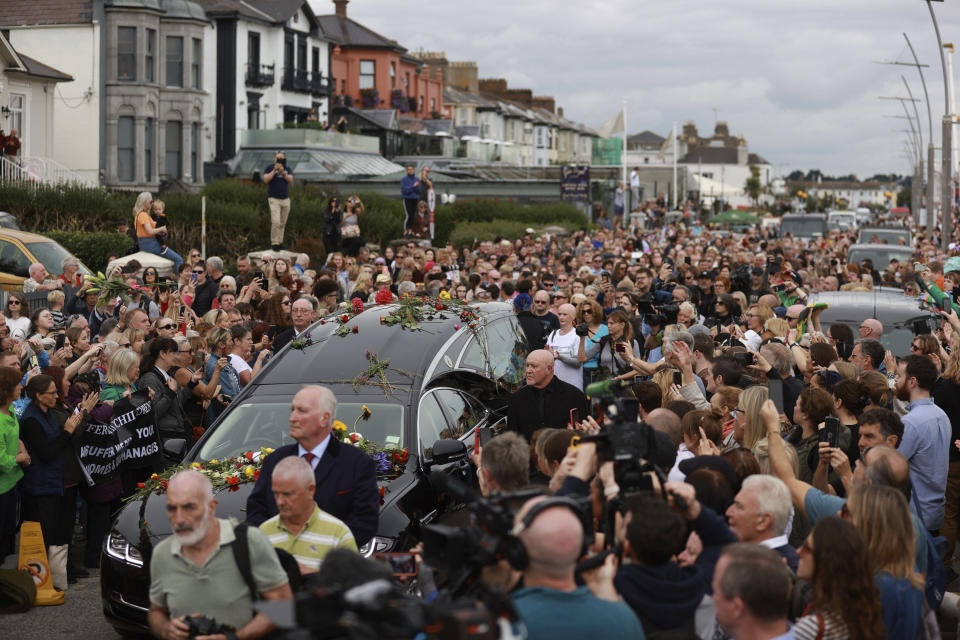 Fans de Sinéad O'Connor rodean su cortejo fúnebre en Bray, la ciudad natal de la cantante en el condado de Wicklow, Irlanda, el martes 8 de agosto de 2023. La familia de O'Connor invitó al público al paseo marítimo de Bray para despedirse de la artista. (Liam McBurney/ PA vía AP)