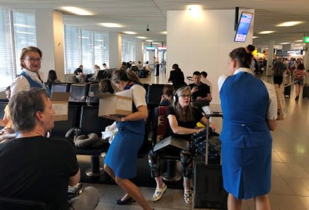 People and staff wait at Amsterdam Schiphol airport