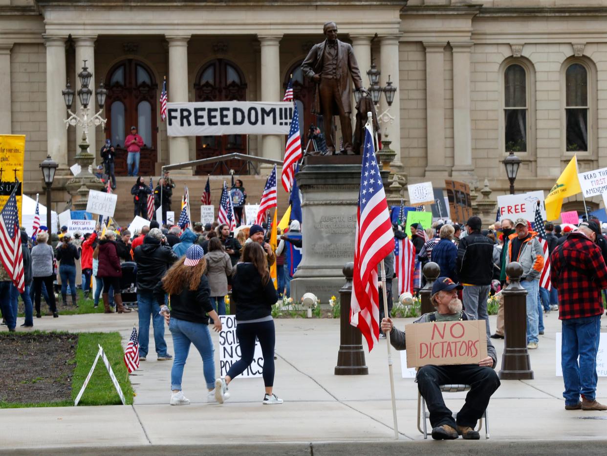 In this April 30, 2020, photo, protesters rally at the State Capitol in Lansing, Mich. Gun-carrying protesters have been a common sight at some demonstrations calling for coronavirus-related restrictions to be lifted. But an armed militia’s involvement in an angry protest in the Michigan statehouse Thursday marked an escalation that drew condemnation and shone a spotlight on the practice of bringing weapons to protest.  (AP Photo/Paul Sancya)