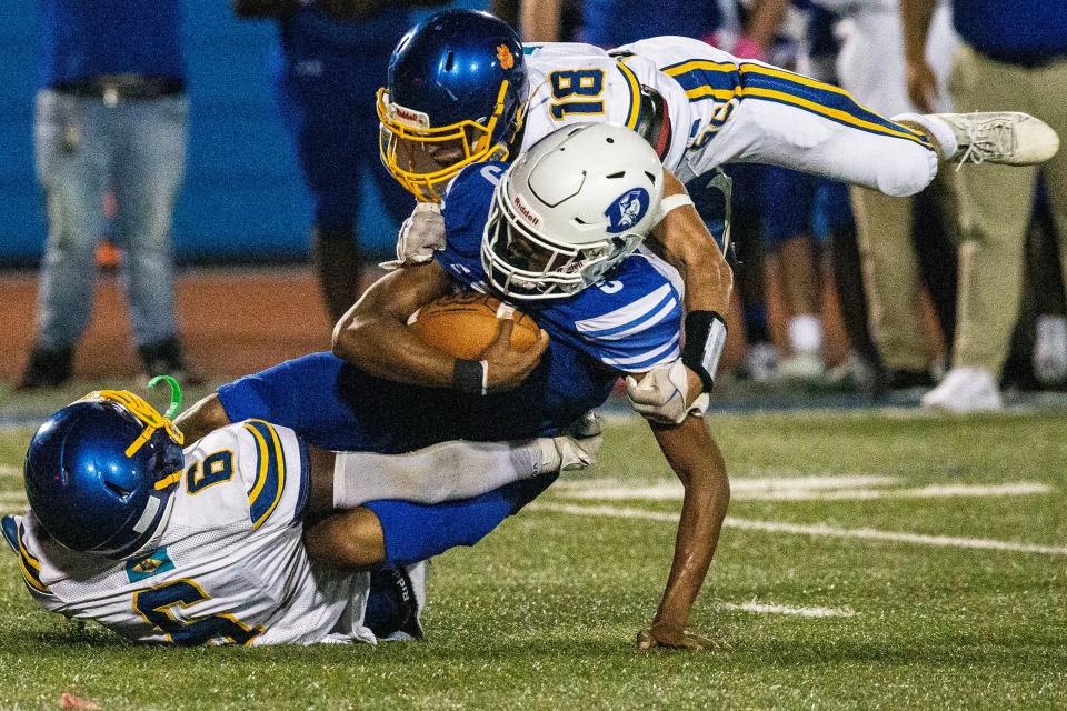 Sussex Central junior Jajuan Sturgis (6) and senior Justin Negron (18) take down Dover quarterback Nahseem Cosme (5) during the Golden Knights' 13-12 win at Dover Stadium on Friday night.