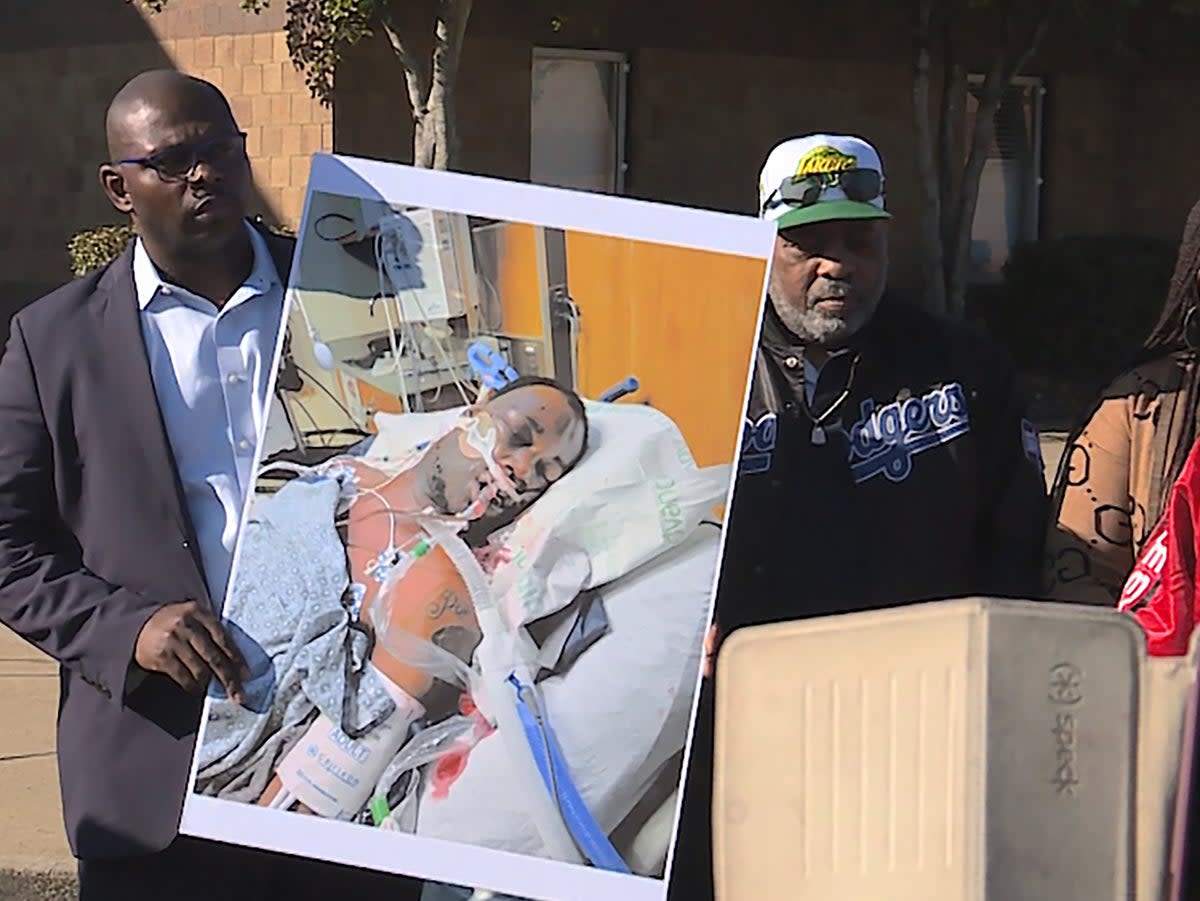 Tyre Nichols' stepfather Rodney Wells, center, stands next to a photo of Nichols in the hospital after his arrest, during a protest in Memphis (AP)