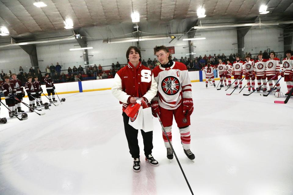 Spaulding High School junior Matt Gould, left, leaves center ice as his good friend and hockey player Owen Nesbitt walks next to him during a ceremony Wednesday at Rochester Ice Arena.