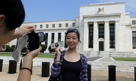 Chinese student Leyna Liu from Shanghai poses with a fake million dollar bill in front of the Federal Reserve building in Washington, in this August 22, 2012 file photo. REUTERS/Larry Downing/Files