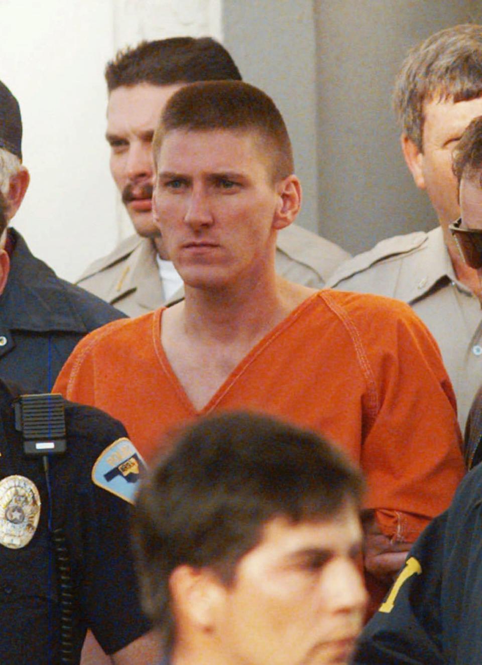 FILE - In this April 21, 1995, file photo, Oklahoma City bombing suspect Timothy McVeigh is escorted by law enforcement officials from the Noble County Courthouse in Perry, Okla., Friday, April 21, 1995. The April 19 bombing of the Alfred P. Murrah Federal Building claimed the lives of 168 people. McVeigh was convicted June 2, 1997, of blowing up the building. The Oklahoma City National Memorial and Museum has scaled back its plans for a 25th anniversary remembrance amid the coronavirus outbreak and will instead offer a recorded, one-hour television program that includes the reading of the names of the 168 people killed in the bombing followed by 168 seconds of silence. (AP Photo/David Longstreath, File)