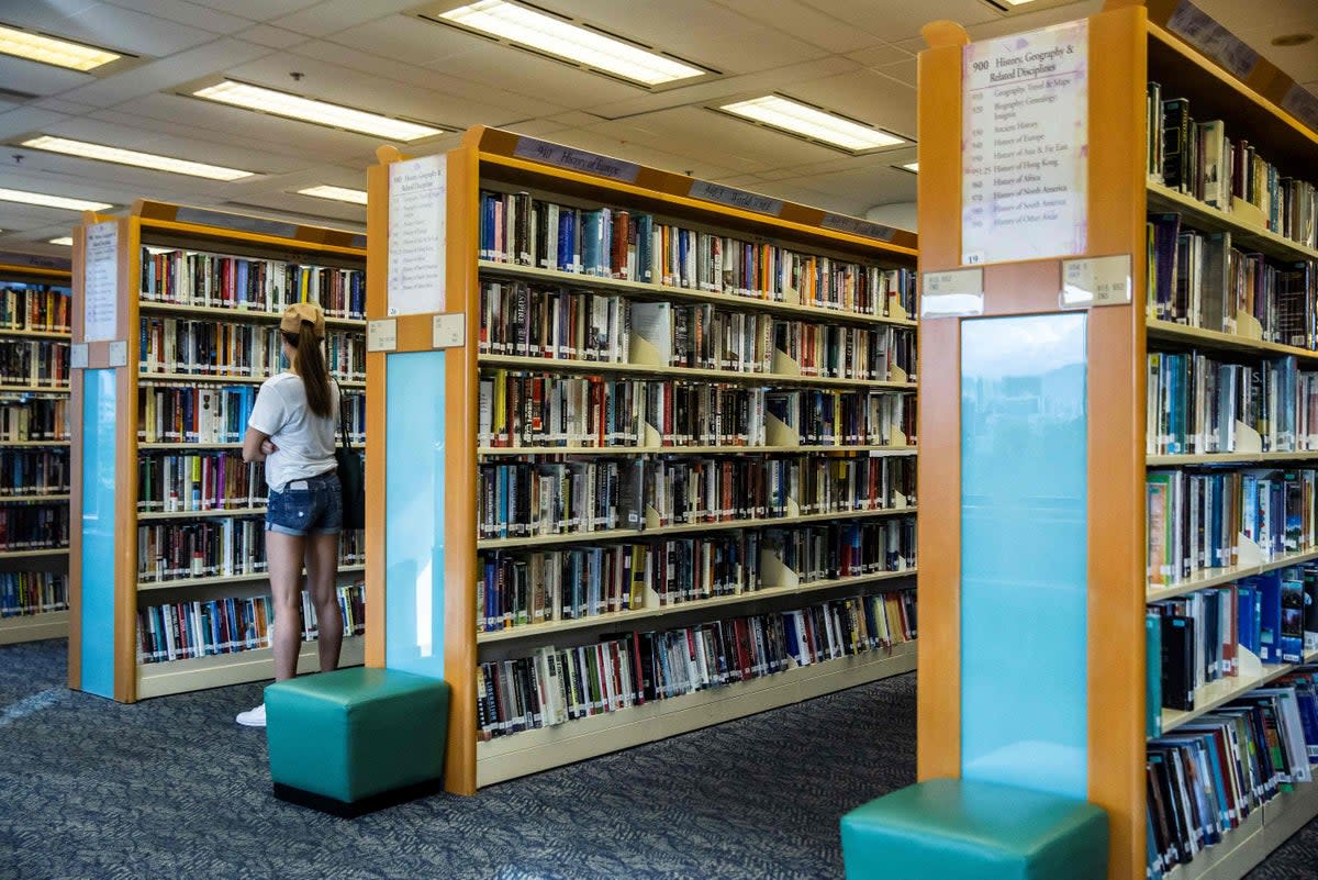 File: A woman looks at books in a public library in Hong Kong (AFP via Getty Images)