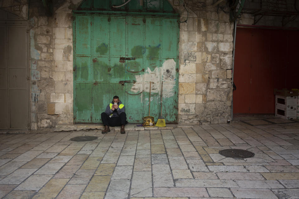 A municipal worker uses his mobile phone in the Old City of Jerusalem, Monday, Dec. 28, 2020 during a third lockdown to curb the spread of the coronavirus. In the early days of the pandemic, a panicked Israel began using a mass surveillance tool on its own people, tracking civilians’ mobile phones to halt the spread of the coronavirus. But months later, the tool’s effectiveness is being called into question and critics say its use has come at an immeasurable cost to the country’s democratic principles. (AP Photo/Maya Alleruzzo)