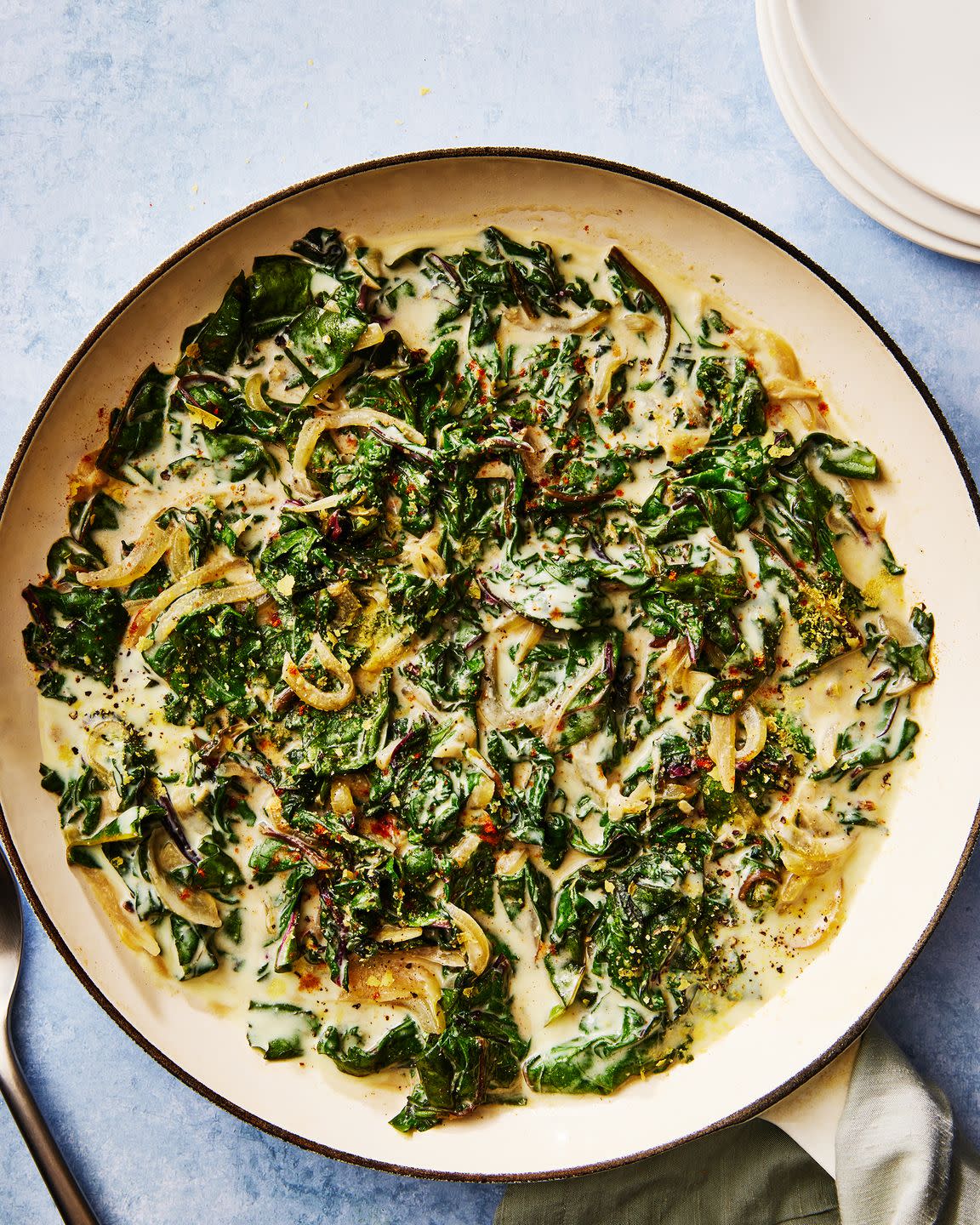 greens in a creamy sauce with onions in a skillet