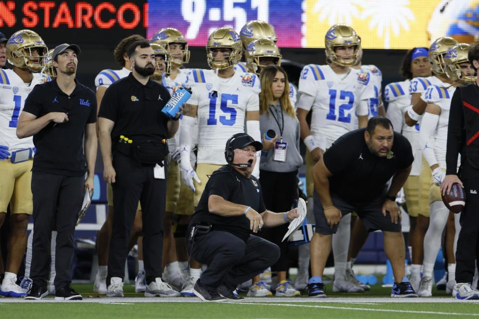 UCLA coach Chip Kelly, crouching on the sideline, reacts to a play during the L.A. Bowl against Boise State.