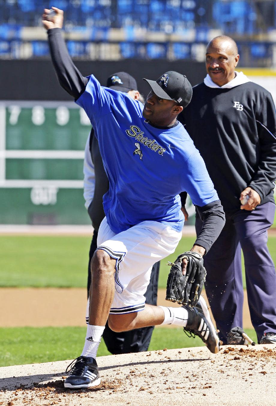 Retired NBA All-Star Tracy McGrady delivers a pitch at the Sugar Land Skeeters baseball stadium as former major league pitcher Scipio Spinks, right, stands near Wednesday, Feb. 12, 2014, in Sugar Land, Texas. McGrady hopes to tryout for the independent Atlantic League Skeeters. (AP Photo/Pat Sullivan)
