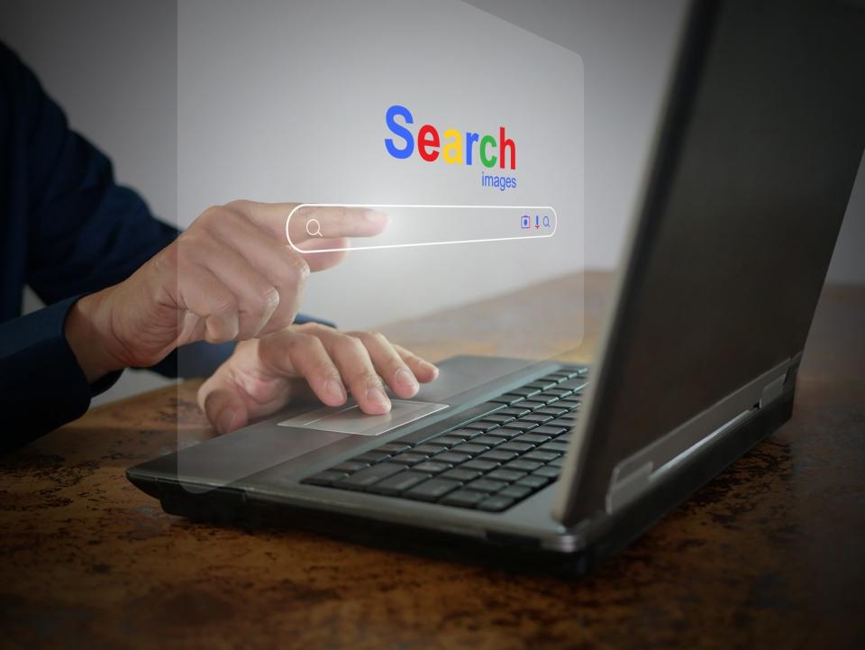 A person uses a search bar on a laptop.