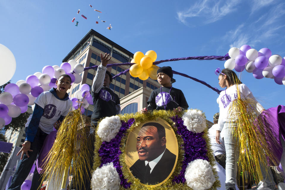 In this Monday, Jan. 15, 2018 photo candy is thrown from the This and That Creative Corner float during The "Original" MLK, Jr. Parade in Houston. For more than two decades, competing MLK Day parades have been held in Houston. This year, the city of Houston threw its official support behind one parade, the 41st annual “Original” MLK, Jr. Parade, hoping the city could unite behind only one parade. But organizers of the other parade, the 25th annual MLK Grande Parade, will still be holding its event and they say they have no plans to stop having their own parade. (Brett Coomer/Houston Chronicle via AP)