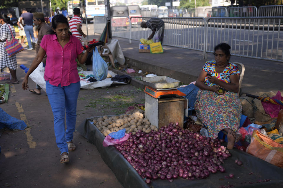 A woman shops at a vegetable market in Colombo, Sri Lanka, Wednesday, Dec. 13, 2023. The International Monetary Fund executive board has approved the release of $ 337 million second tranche of a bailout package to help Sri Lanka recover from its worst economic crisis. (AP Photo/Eranga Jayawardena)