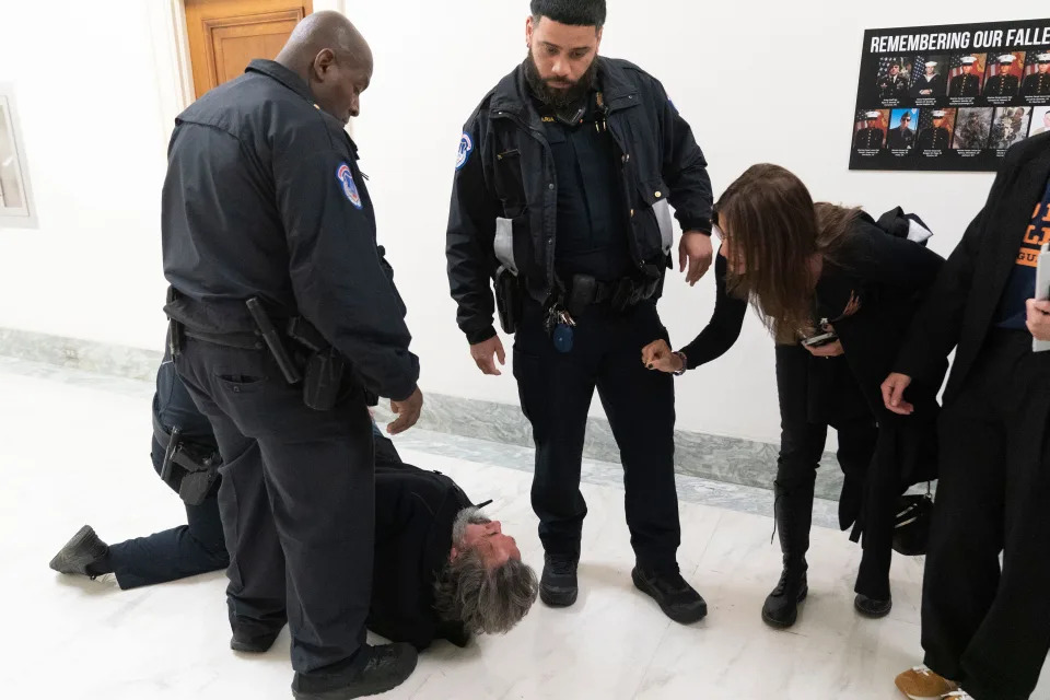 Manuel Oliver, the father of Joaquin Oliver, one of the victims of the 2018 mass shooting at Marjory Stoneman Douglas High School in Parkland, Fla., is removed from the hearing room for disturbing a hearing on Capitol Hill in Washington, Thursday, March 23, 2023. With Manuel Oliver is his wife, Patricia Oliver, at right.