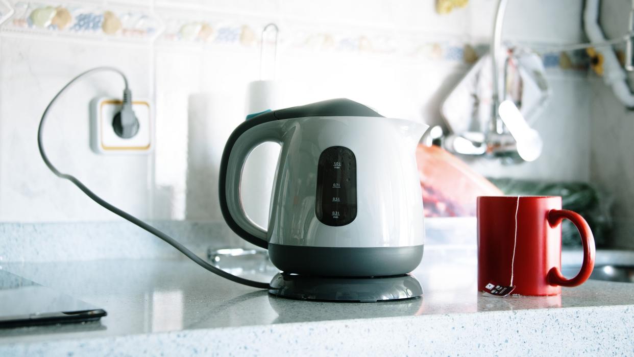 Modern electric kettle and tea cup stock photo