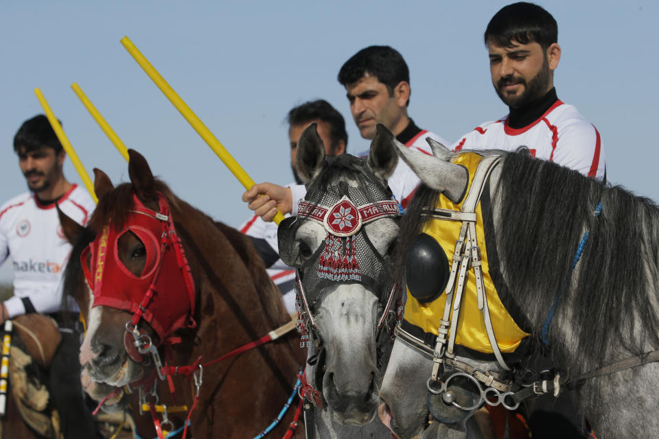 Riders, members of the Dadas (Comrades) local sporting club, pose for photographs prior to a game of Cirit, a traditional Turkish equestrian sport that dates back to the martial horsemen who spearheaded the historical conquests of central Asia's Turkic tribes, between the Comrades and the Experts local sporting clubs, in Erzurum, eastern Turkey, Friday, March 5, 2021. The game that was developed more than a 1,000 years ago, revolves around a rider trying to spear his or her opponent with a "javelin" - these days, a rubber-tipped, 100 centimeter (40 inch) length of wood. A rider from each opposing team, which can number up to a dozen players, face each other, alternately acting as the thrower and the rider being chased. Cirit was popular within the Ottoman empire, before it was banned as in the early 19th century. However, its popularity returned as is now one of many traditional sports encouraged by the government and tournaments are often arranged during festivals or to celebrate weddings. (AP Photo/Kenan Asyali)